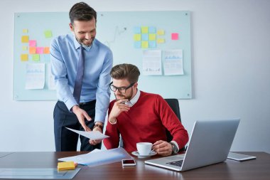 Ofiste sözleşme belgelerini okuyan iki iş ortağı