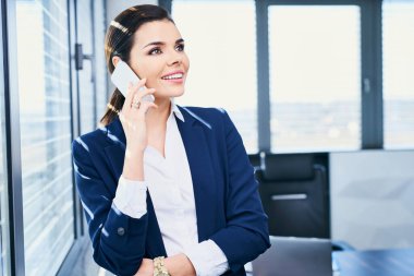 İş kadını ofisteyken telefonda konuşuyor.