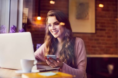 Kahve dükkanından dizüstü bilgisayarla çalışan güzel genç bir kadın.