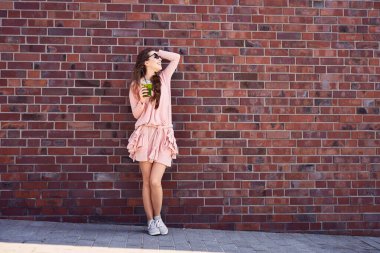 Şehir caddesinde smoothie ile mutlu genç bir kadın