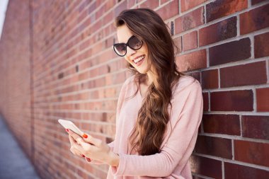 Şehir caddesinde telefonunu kullanan güzel genç bir kadın.