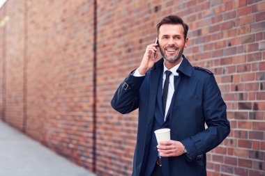Güvenilir orta yaşlı işletme yöneticisi önemli telefon görüşmeleri yapıyor.