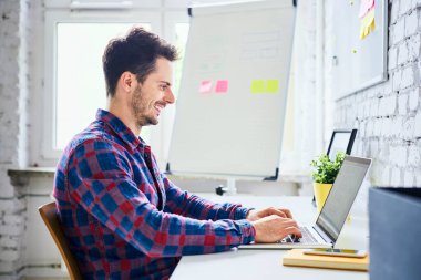 Web tasarımcısı ve hipster ofiste dizüstü bilgisayarda çalışıyor.