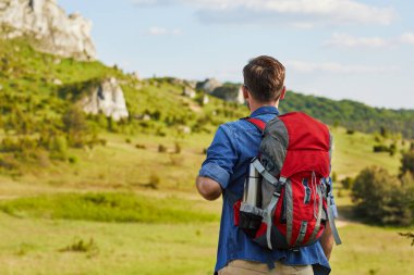 Yaz gezisi sırasında sırt çantasıyla dağlarda gezen bir adam.