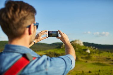 Yürüyüş yapan adam akıllı telefonla fotoğraf çekiyor.