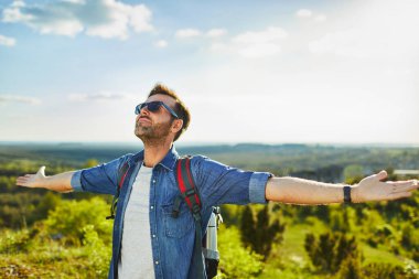 Kaldırılmış ellerle yürüyüş yapan adam yaz günlerinde yürüyüş yapmaktan zevk alıyor.