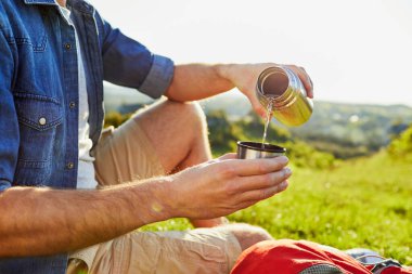  Adam yorucu bir yürüyüşten sonra kendine bir bardak su dolduruyor.