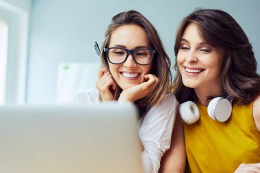 İnternette dizüstü bilgisayarda sörf yapan iki kız arkadaşın yakın çekimi.