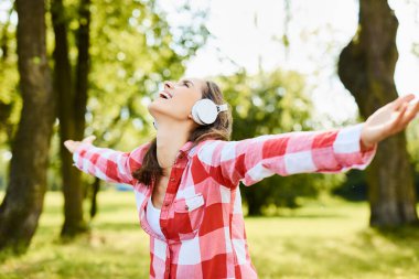 Kollarını açıp parka bakan genç bir kadın.