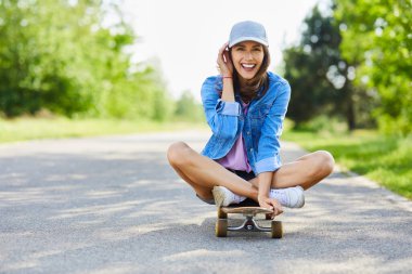 Güzel genç bir kadın dışarıda, tahtada oturuyor ve gülümsüyor.