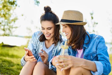 İki kadın dışarıda oturmuş limonata içiyor.