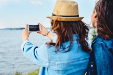 Dışarıdaki genç kadınlar akıllı telefonlarıyla fotoğraf çekiyorlar.. 