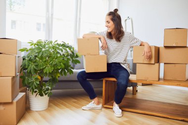 Çekici, neşeli genç bayan, yeni dairesinde her tarafında kutular olan masada oturuyor.