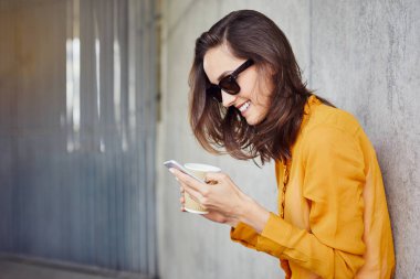 Neşeli genç kadın manifatura ve kahve duvara yaslanmış iken kentsel dış ortamda holding