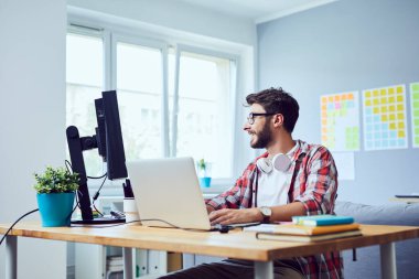 Yaratıcı gülümseyen genç adam rahat ev ofisinde yeni bir iş kuruyor.