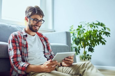 Genç gülümseyen bir adamın tablet kullanırken çekilmiş gizli bir fotoğrafı.