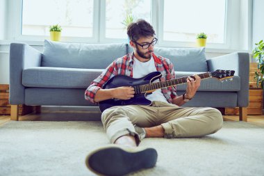 Evde elektrik gitar çalmak genç adam