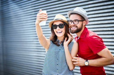 Genç çift gülümsüyor ve dışarıda selfie çekiyor