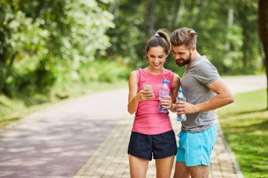 Genç çift yazın koşarken telefona bakıyor.