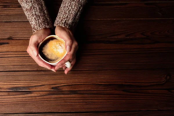 木製の背景に女性の手とコーヒー — ストック写真