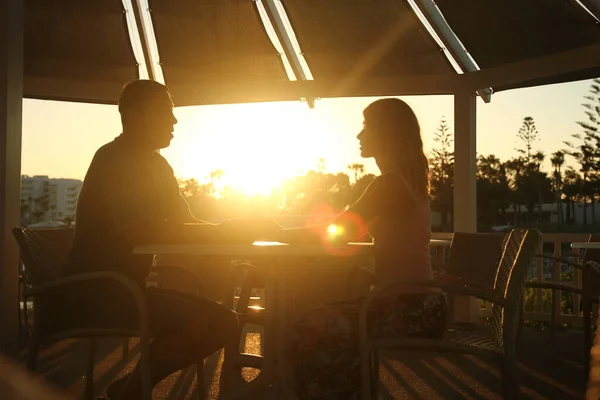 happy couple at a table by the sea at sunset nature
