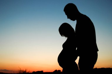 Günbatımı konseptinde hamile bir çiftin silueti mutlu bir aile.