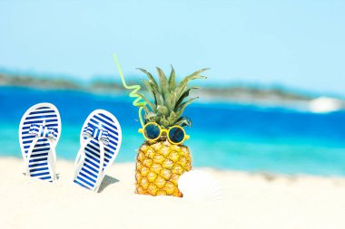 Deniz kenarında ananas ve kıyı arka planında spor ayakkabıları.