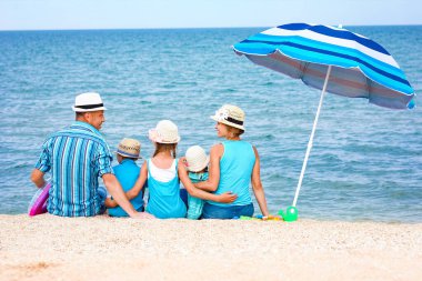 Sahilde kumsalda oynayan mutlu bir aile.