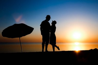 Gün batımında deniz kenarında mutlu bir çift doğada gezici bir siluette