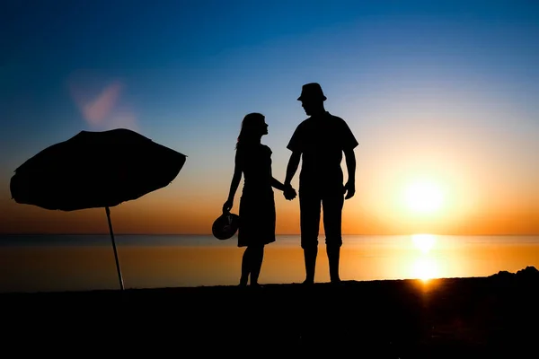 Happy couple by the sea at sunset on travel silhouette in nature