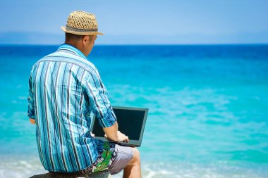 Happy man guy with laptop near the seashore weekend travel