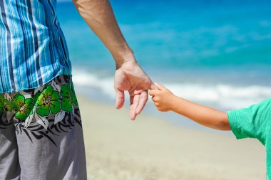 Mutlu bir ebeveynin elleri ve deniz kıyısındaki çocuk doğa yolculuğunda.