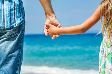 Mutlu bir ebeveynin elleri ve deniz kıyısındaki çocuk doğa yolculuğunda.