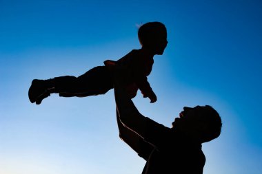 a parent with a child playing on the beach silhouette