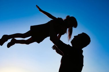 a parent with a child playing on the beach silhouette