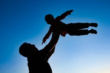 a parent with a child playing on the beach silhouette