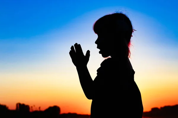 Silhouette of man praying at sunset background