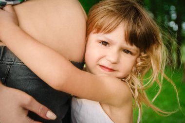 Happy pregnant woman with a child on the nature in the park