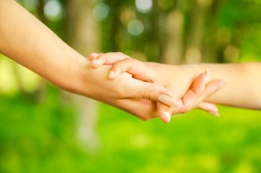 Mutlu aile ve çocuk parkta el ele tutuşuyor.