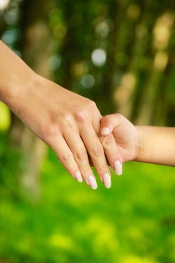 Mutlu aile ve çocuk parkta el ele tutuşuyor.