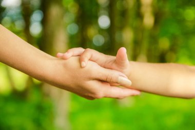 Mutlu aile ve çocuk parkta el ele tutuşuyor.