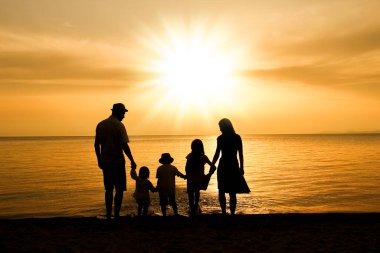 Doğada mutlu bir aile deniz kenarında bir siluette