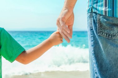 Mutlu bir ebeveynin elleri ve deniz kıyısındaki çocuk doğa yolculuğunda.