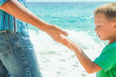 Mutlu bir ebeveynin elleri ve deniz kıyısındaki çocuk doğa yolculuğunda.