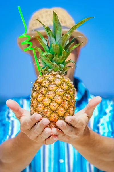 Pineapple in the hands of a man by the sea in nature on a journey background