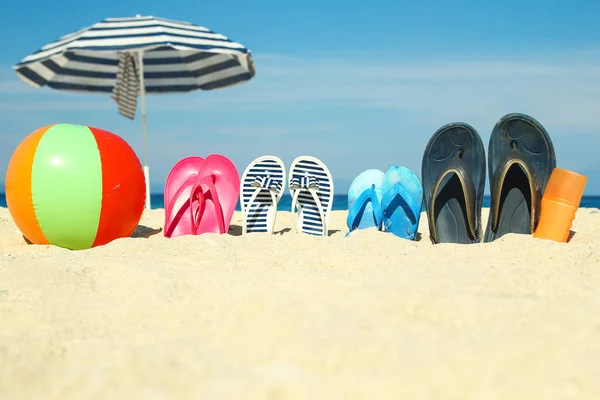 Plaj yaz tatili afişi. Parmak arası terlik ve şapkalı, üzerinde tahta ve top olan okyanus kıyısındaki kumda. Deniz kıyısında yaz aksesuarları. Tropik tatil ve rahat seyahat konsepti. Üst görünüm ve kopyalama alanı.