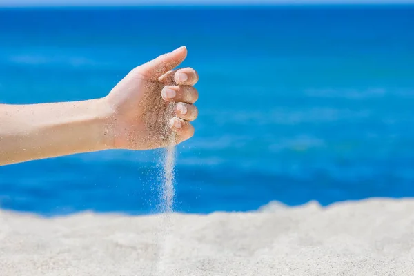 Hands pour sand off the sea on nature on a journey. Vacations at sea sand time passes.