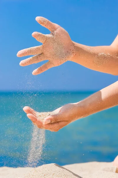 Hands pour sand off the sea on nature on a journey. Vacations at sea sand time passes.