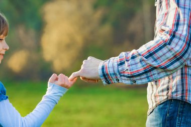 beautiful hands of parent and child outdoors in the park clipart