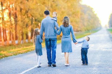 Mutlu bir aile parkta yol boyunca yürüyor.